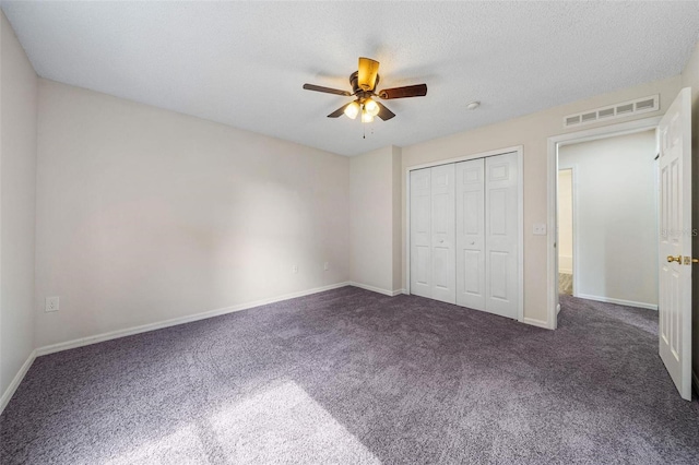 unfurnished bedroom featuring ceiling fan, a closet, dark carpet, and a textured ceiling