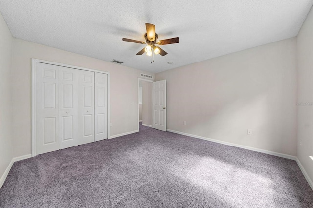 unfurnished bedroom with a textured ceiling, carpet floors, a closet, and ceiling fan