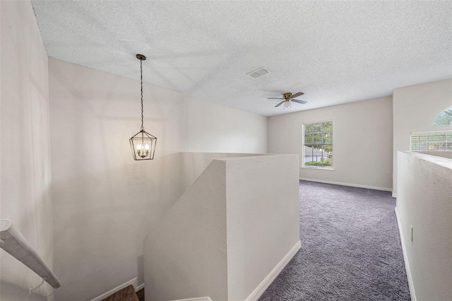 hall with carpet, a chandelier, and a textured ceiling