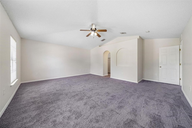 interior space with a textured ceiling, ceiling fan, dark carpet, and lofted ceiling