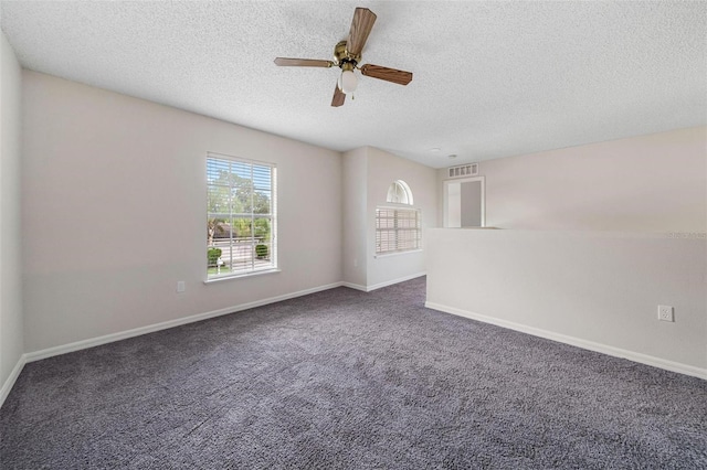 spare room with ceiling fan, dark carpet, and a textured ceiling