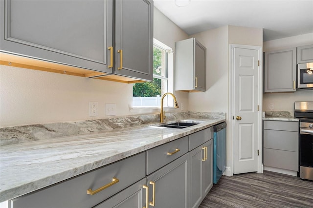 kitchen featuring gray cabinetry, light stone countertops, sink, dark hardwood / wood-style flooring, and appliances with stainless steel finishes