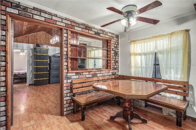dining room with breakfast area, ceiling fan, brick wall, and vaulted ceiling