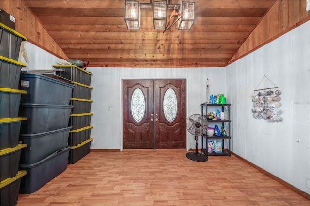 entrance foyer featuring wood walls, light hardwood / wood-style flooring, wood ceiling, and lofted ceiling