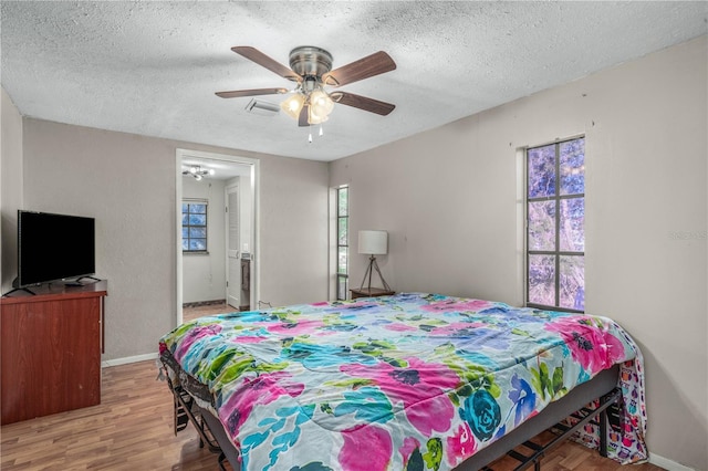 bedroom with multiple windows, ceiling fan, wood-type flooring, and a textured ceiling