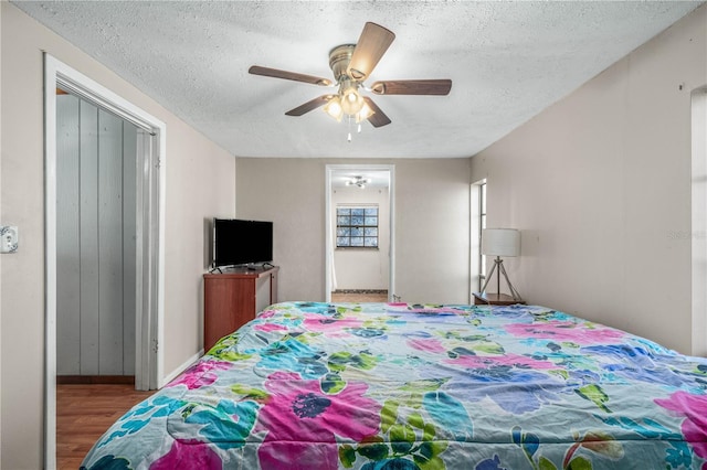 bedroom featuring ceiling fan, wood-type flooring, and a textured ceiling