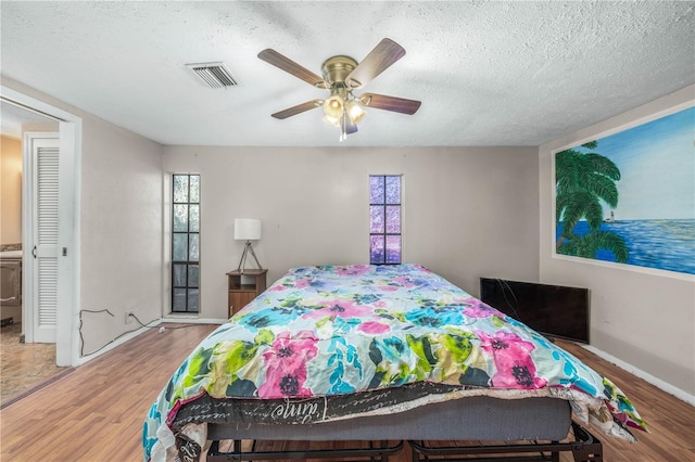 bedroom featuring a textured ceiling, light hardwood / wood-style floors, and ceiling fan