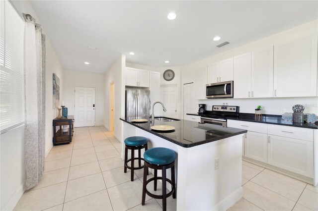 470 Lake Shore Pkwy, Davenport, FL 33896 - kitchen featuring stainless steel appliances, a sink, light tile patterned floors, dark countertops, and a breakfast bar