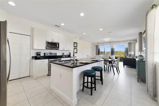 kitchen with an island with sink, sink, white cabinets, and stainless steel appliances