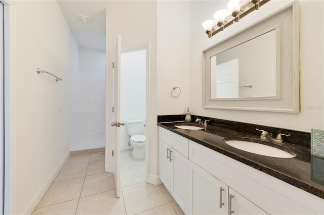 bathroom with tile patterned flooring, vanity, tiled shower, and toilet