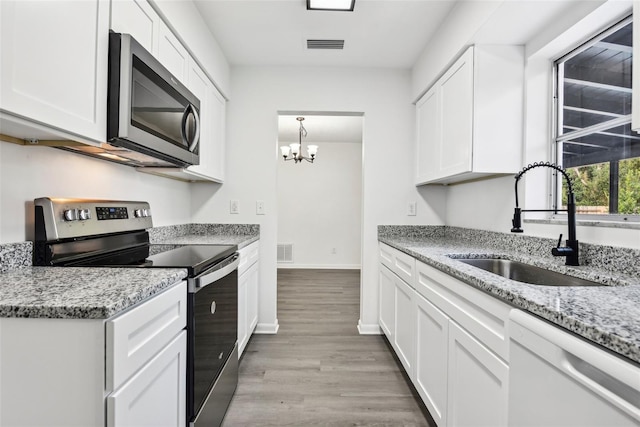 kitchen with stainless steel appliances, sink, light hardwood / wood-style flooring, a notable chandelier, and white cabinets