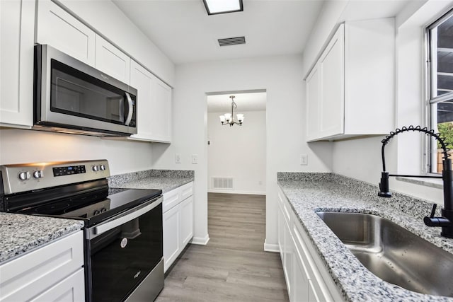 kitchen with white cabinetry, an inviting chandelier, light hardwood / wood-style floors, and appliances with stainless steel finishes