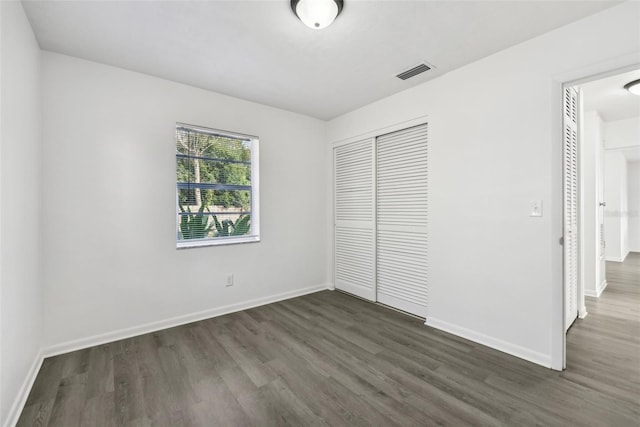 unfurnished bedroom featuring a closet and dark wood-type flooring