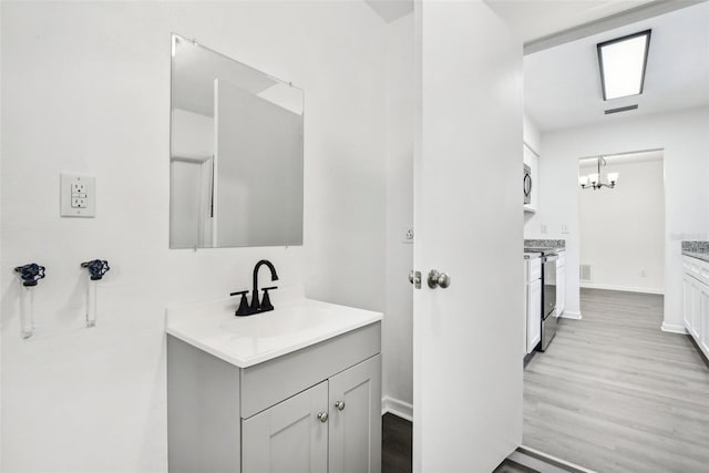 bathroom featuring vanity, wood-type flooring, and a notable chandelier