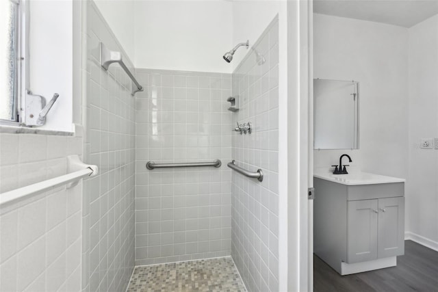 bathroom featuring hardwood / wood-style floors, vanity, and a tile shower