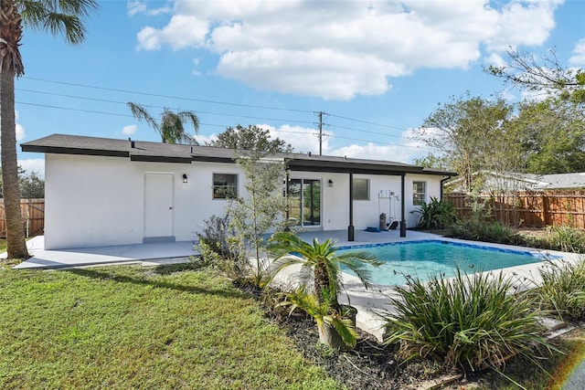 rear view of property featuring a patio area, a fenced in pool, and a yard