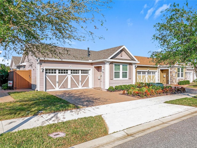 ranch-style home with an attached garage, decorative driveway, and fence