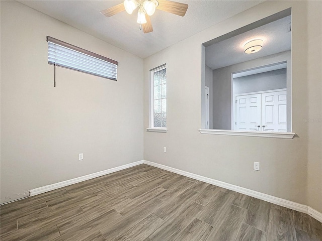 empty room featuring baseboards, a textured ceiling, wood finished floors, and a ceiling fan