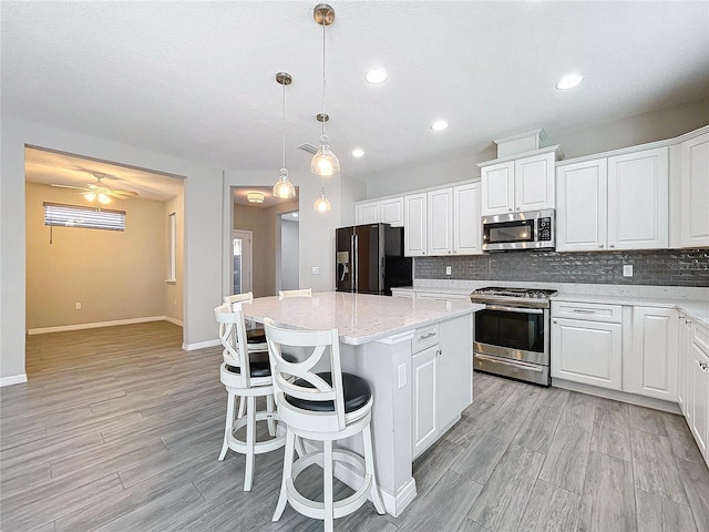 kitchen with light wood finished floors, backsplash, appliances with stainless steel finishes, and a center island