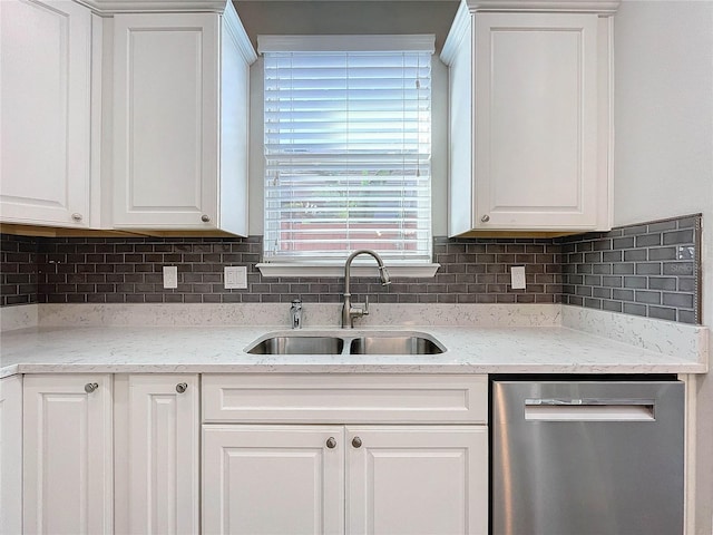 kitchen featuring stainless steel dishwasher, white cabinets, tasteful backsplash, and a sink