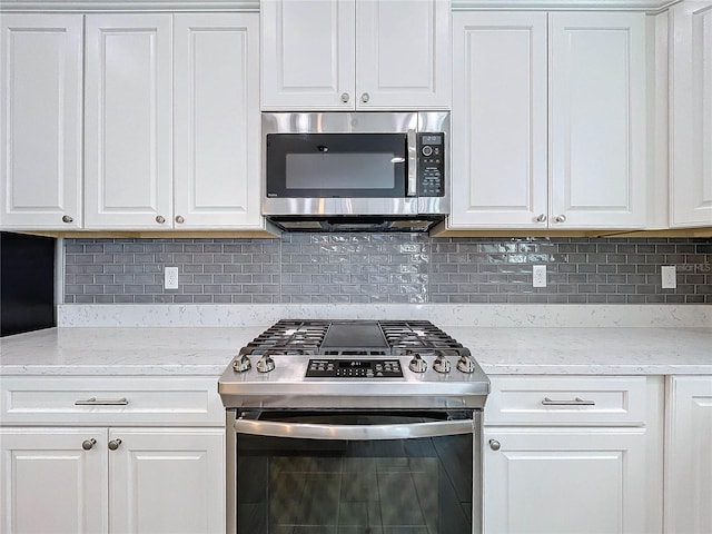 kitchen with white cabinetry, light stone countertops, tasteful backsplash, and stainless steel appliances