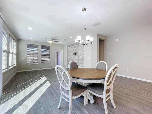 dining space with ceiling fan with notable chandelier and dark hardwood / wood-style floors