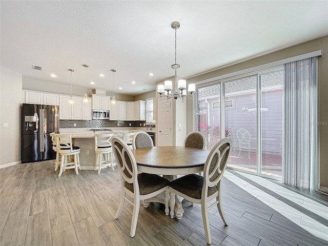 dining room with baseboards, light wood-style floors, visible vents, and a chandelier