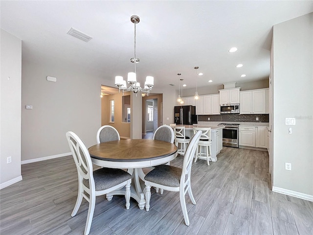 dining room with light wood-type flooring and a chandelier