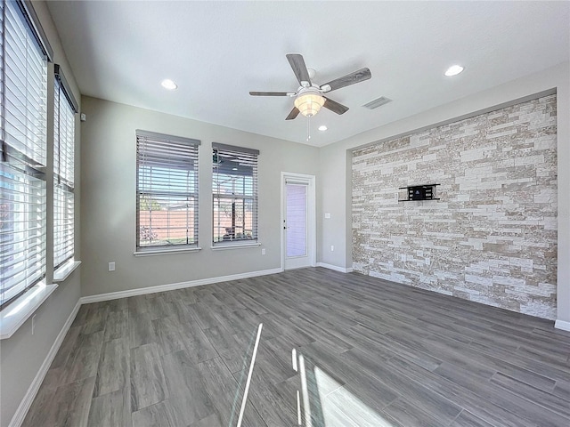 unfurnished living room with visible vents, baseboards, wood finished floors, and a ceiling fan