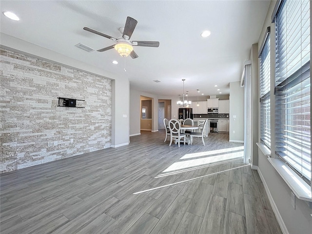 unfurnished living room with hardwood / wood-style floors and ceiling fan with notable chandelier