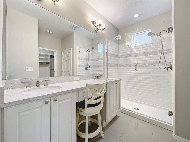 bathroom featuring tile patterned flooring, vanity, a textured ceiling, and walk in shower