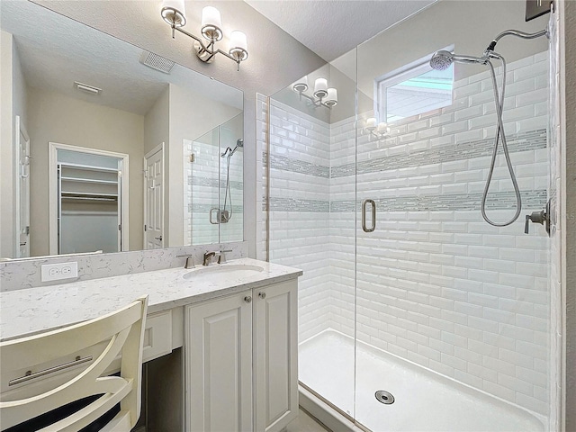 full bathroom with visible vents, a textured ceiling, a stall shower, and vanity