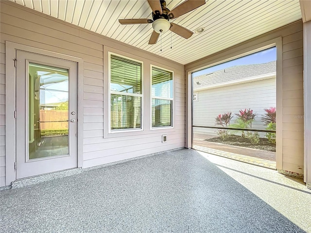 unfurnished sunroom featuring wood ceiling and a ceiling fan