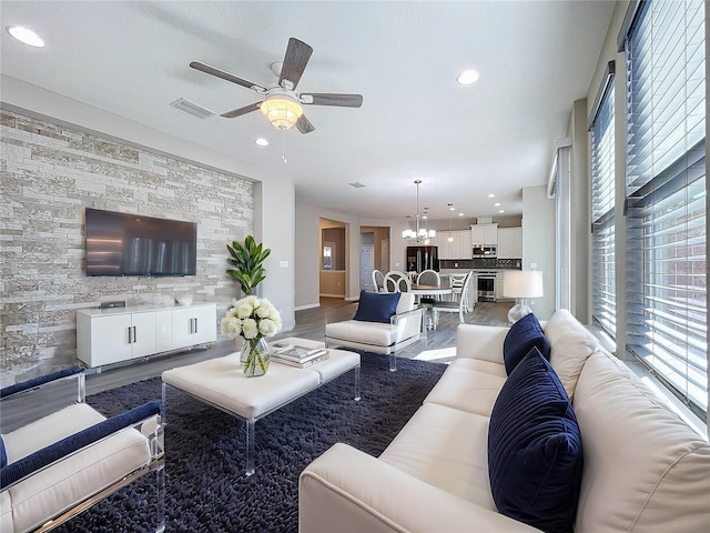 living room with ceiling fan with notable chandelier, light wood-style floors, recessed lighting, and visible vents