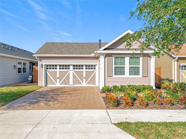 ranch-style house with decorative driveway, an attached garage, and a shingled roof