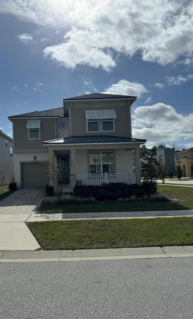 view of front of house featuring covered porch, a garage, and a front lawn