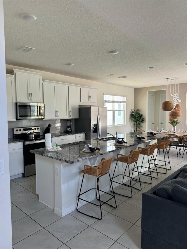 kitchen with light tile patterned floors, a spacious island, white cabinetry, and appliances with stainless steel finishes