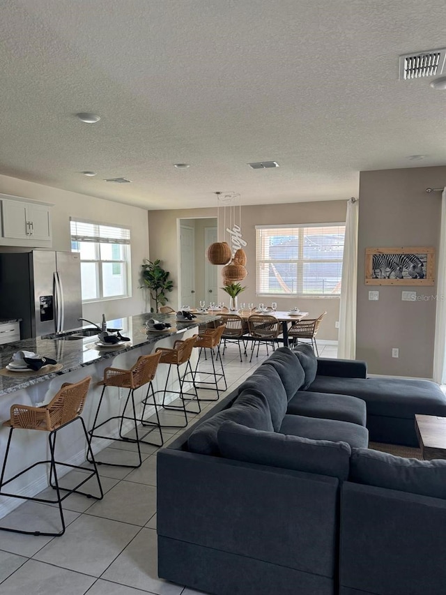 living room with sink, light tile patterned floors, and a textured ceiling