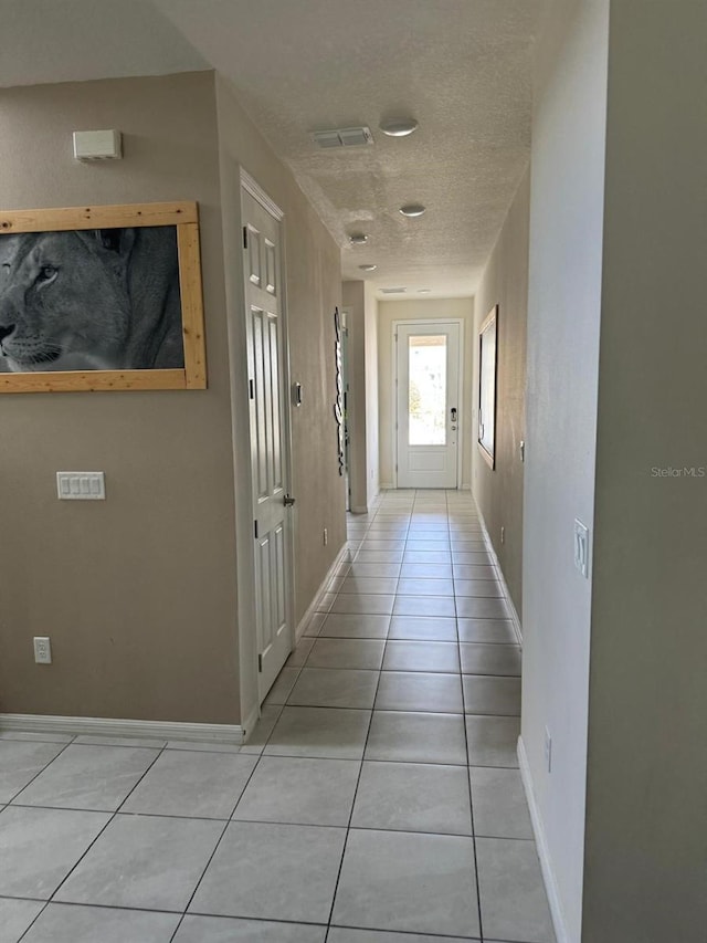 corridor featuring a textured ceiling and light tile patterned flooring