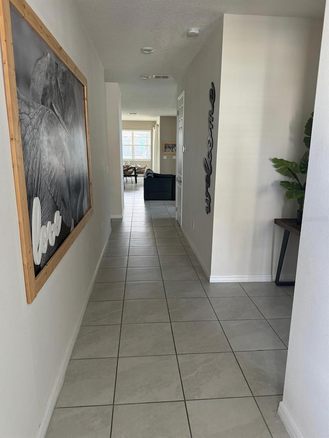 hallway with tile patterned floors and a textured ceiling