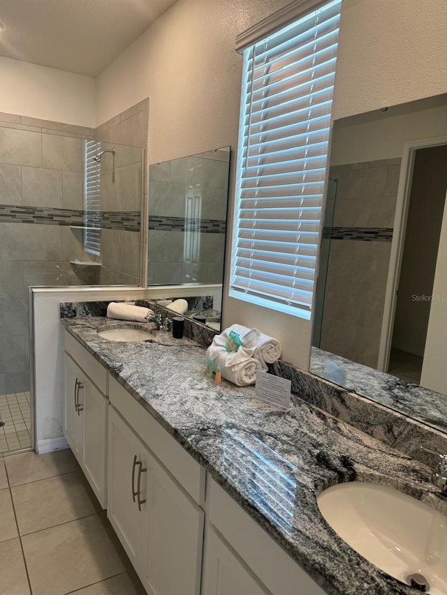 bathroom with a tile shower, vanity, and tile patterned floors