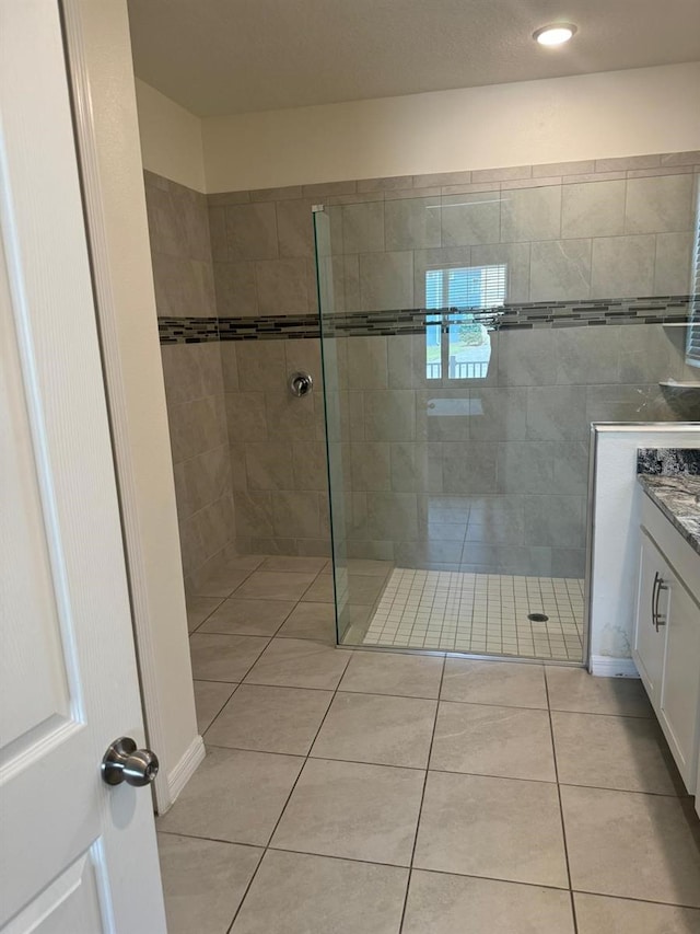 bathroom with a tile shower, tile patterned flooring, and vanity