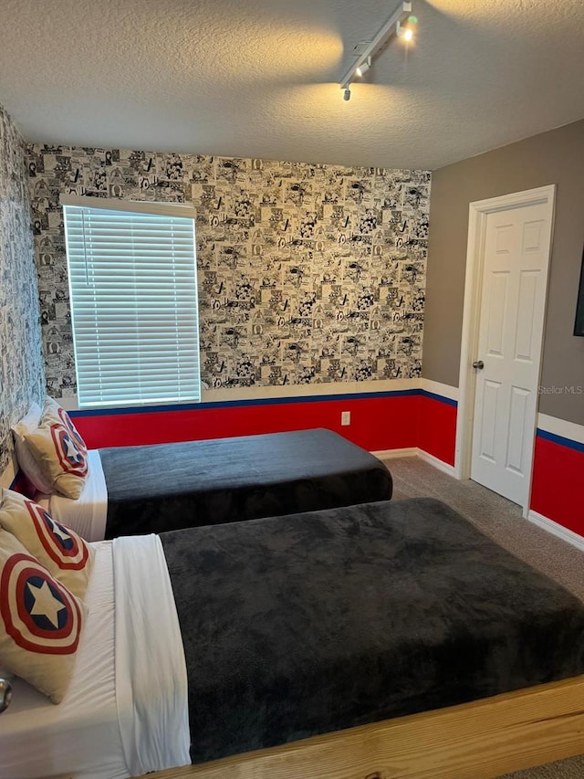 carpeted bedroom with a textured ceiling and track lighting