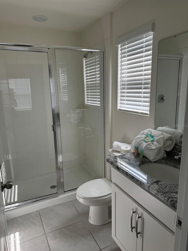 bathroom with tile patterned floors, vanity, a shower with shower door, and toilet