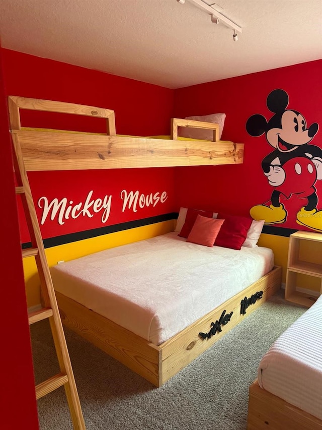 bedroom with a textured ceiling, carpet floors, and rail lighting