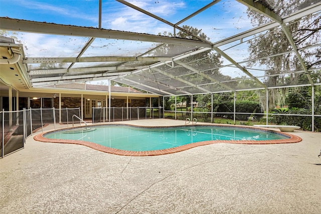 view of swimming pool with glass enclosure, a diving board, and a patio area