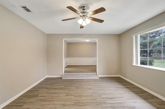 spare room featuring ceiling fan, a textured ceiling, and light hardwood / wood-style flooring