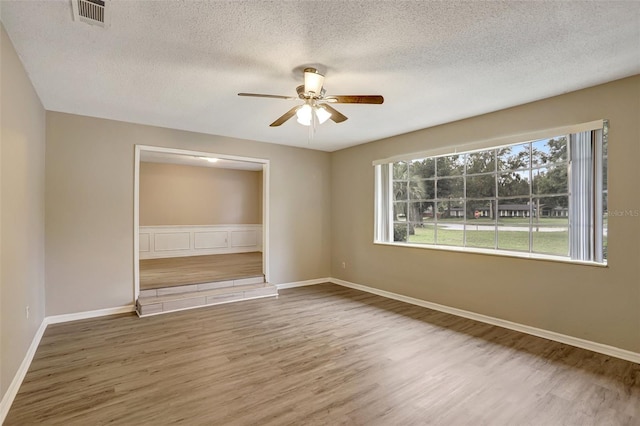 spare room with ceiling fan, a textured ceiling, and hardwood / wood-style flooring