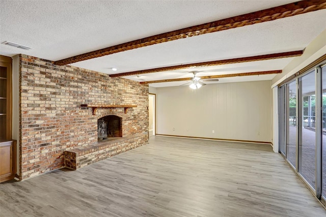 unfurnished living room with beam ceiling, a fireplace, hardwood / wood-style floors, and a textured ceiling