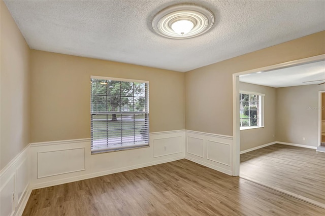 spare room with ceiling fan, light hardwood / wood-style floors, and a textured ceiling